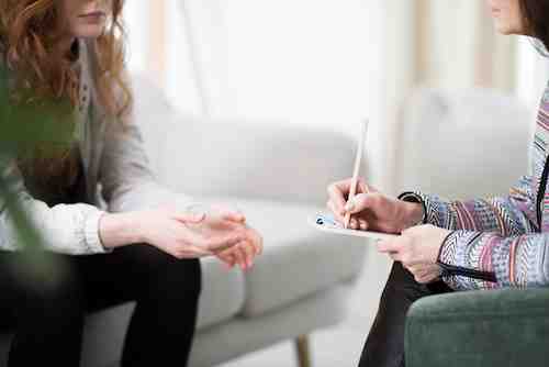 A close-up of a clinical counselling session where a professional utilises 12 step facilitation therapy to help a client engage with recovery programs.
