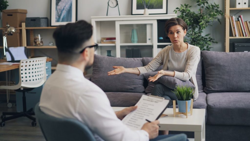 A professional counselor reviewing a checklist while listening to a client, representing comprehensive addiction assessment services