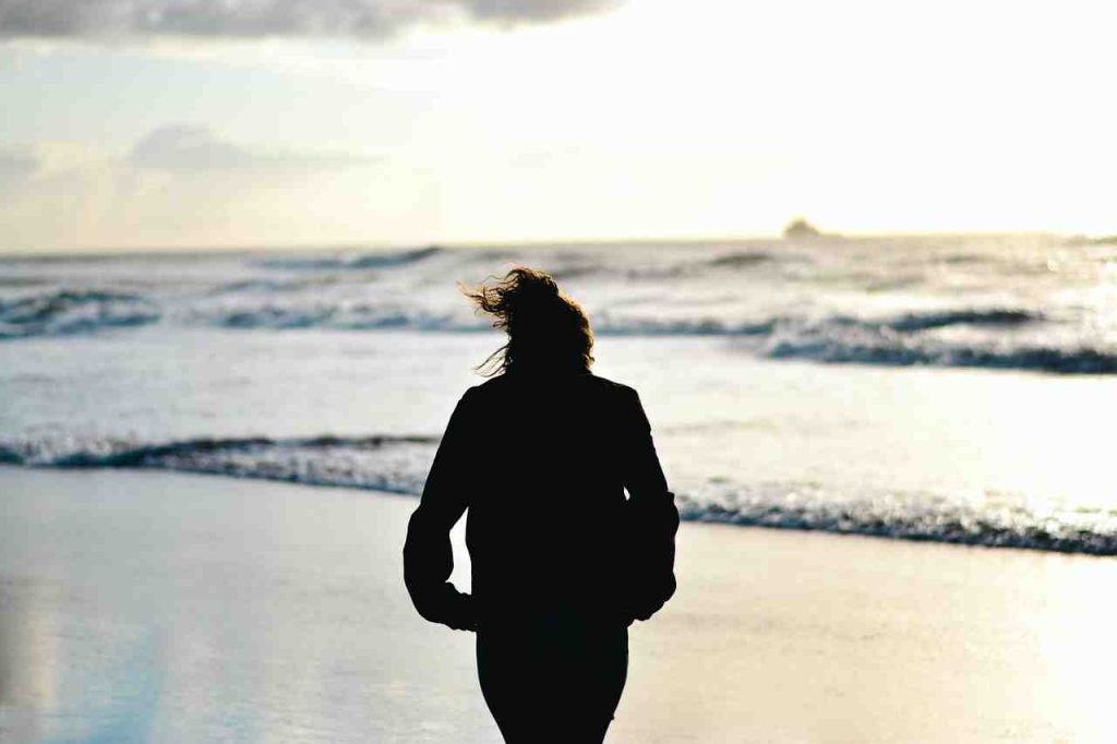 A person looking out at a calm Australian beach at sunrise, reflecting on their recovery journey